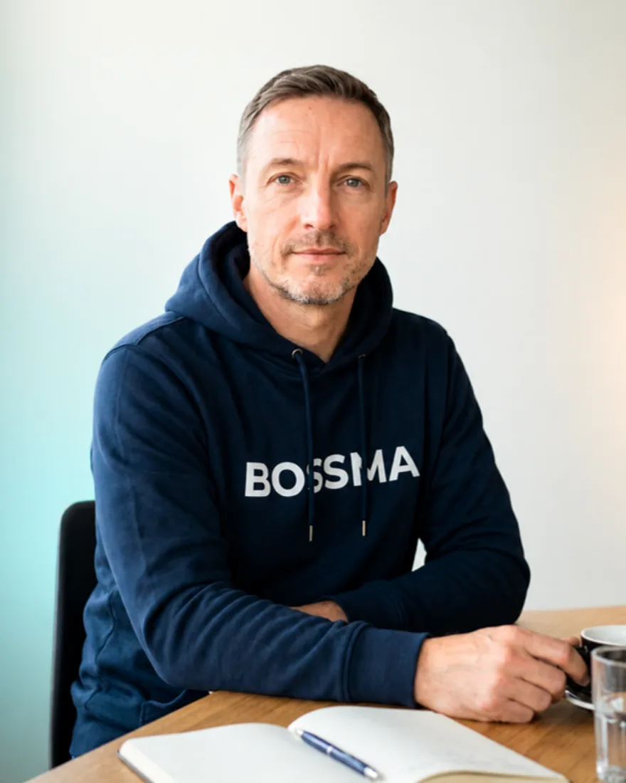 Nico Schulz im dunkelblauen BOSSMA-Hoodie am Schreibtisch mit Notizbuch und Kaffee